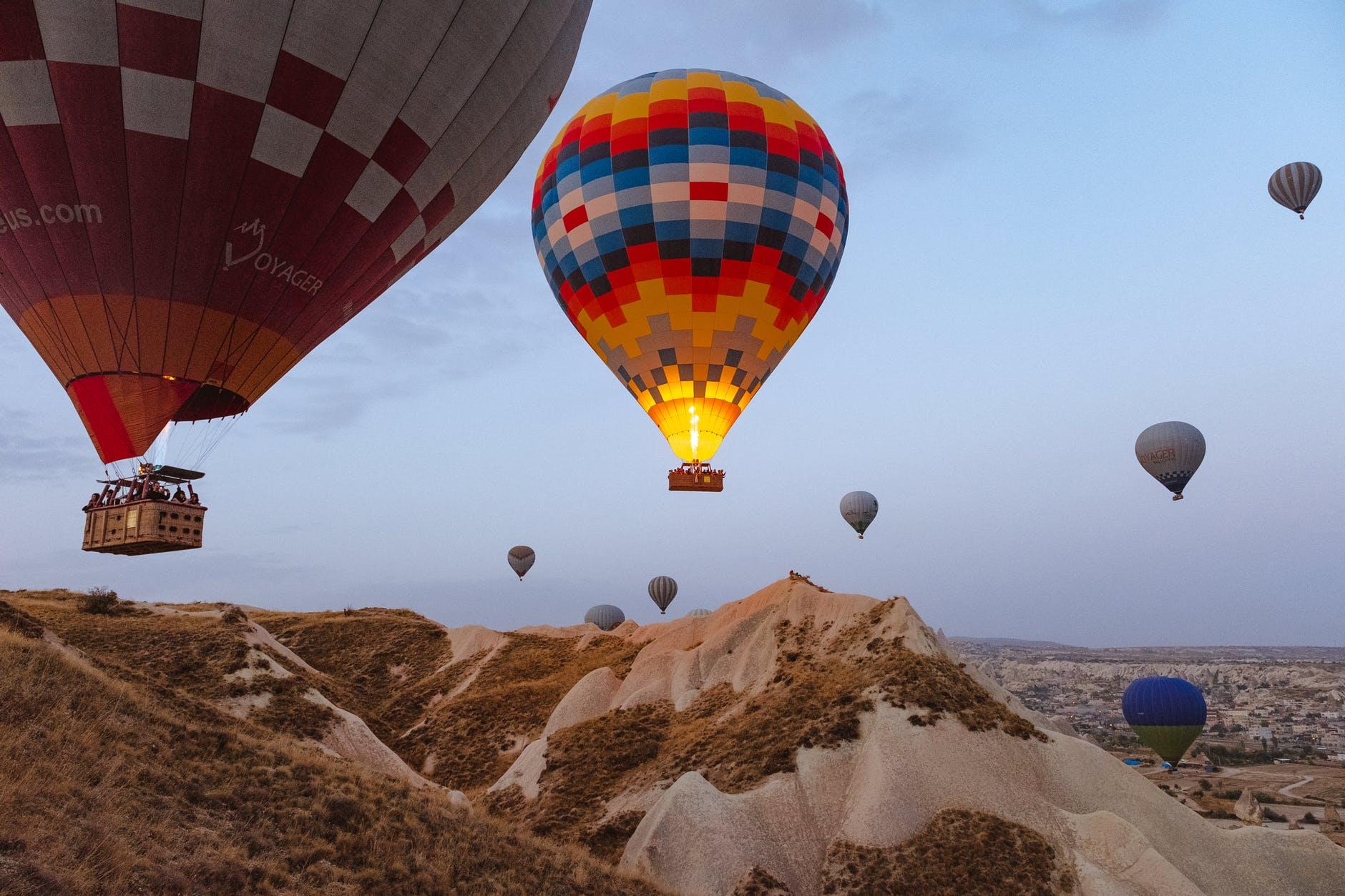 Hot air balloons rising above a desert hill