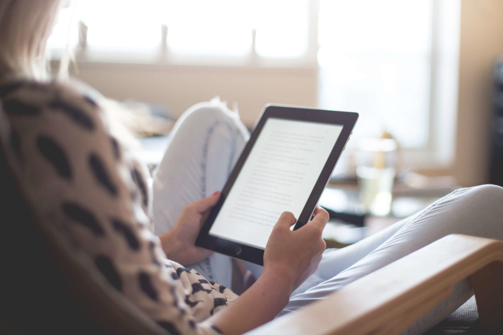 Girl holding up and reading from a Kindle